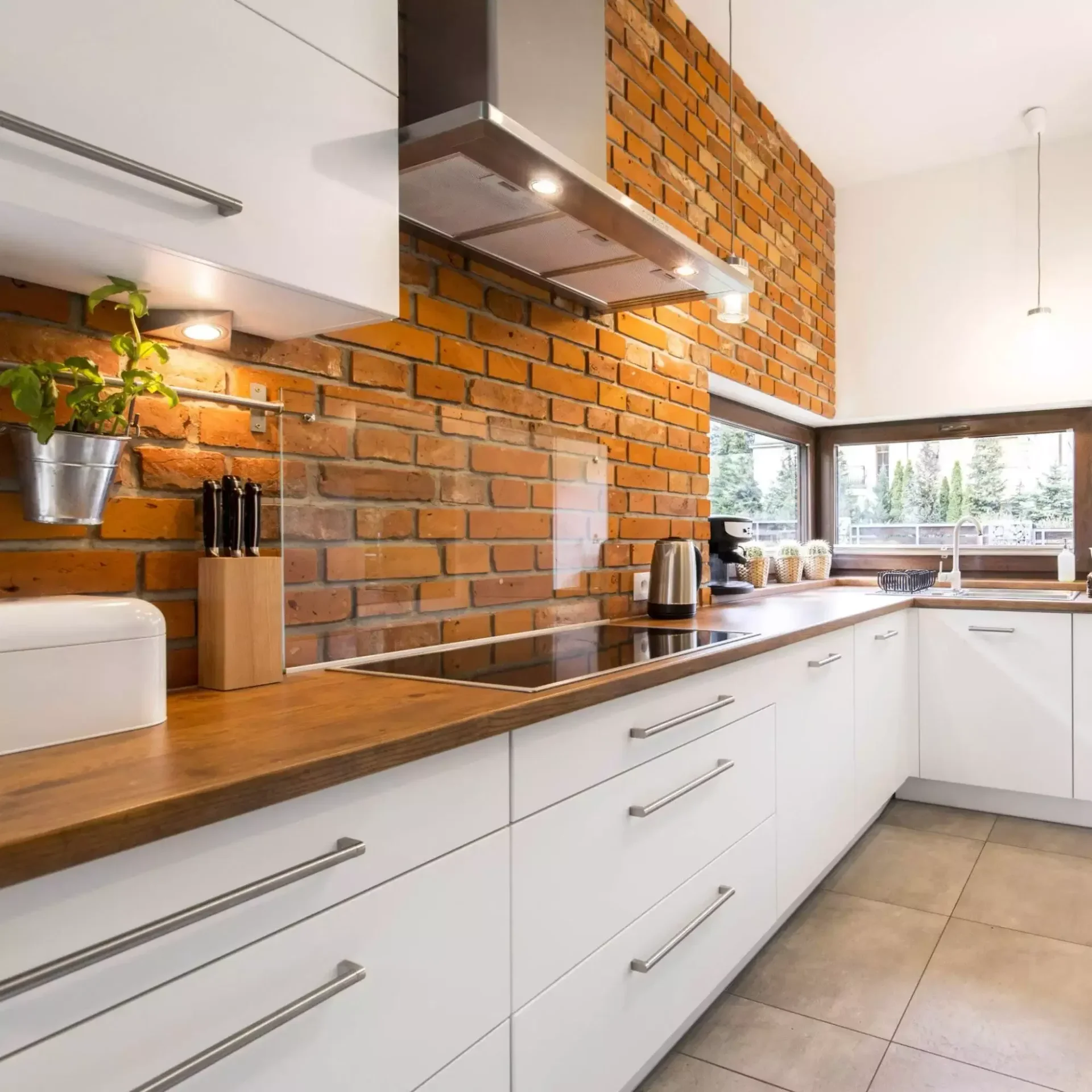 a kitchen with brick wall and white cabinets