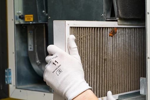 HVAC technician replacing a dirty air filter — spring AC maintenance in northern Utah