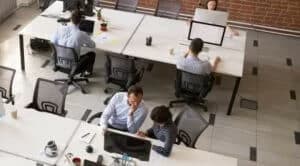 Employees working together in modern open office space, corporate group team employees using computers, talking, discuss project, colleagues in coworking, collaboration, teamwork concept, top view