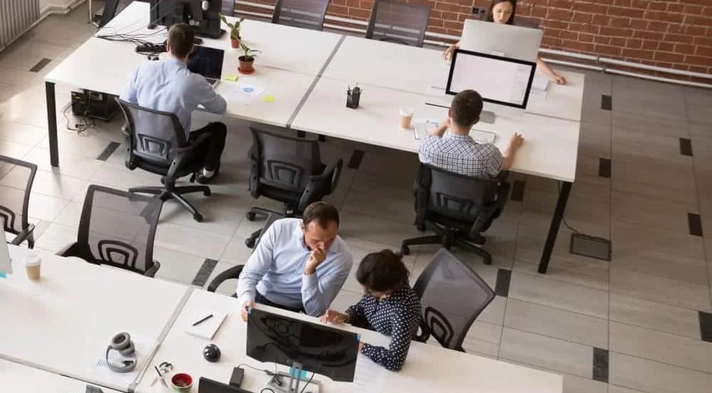 Employees working together in modern open office space, corporate group team employees using computers, talking, discuss project, colleagues in coworking, collaboration, teamwork concept, top view