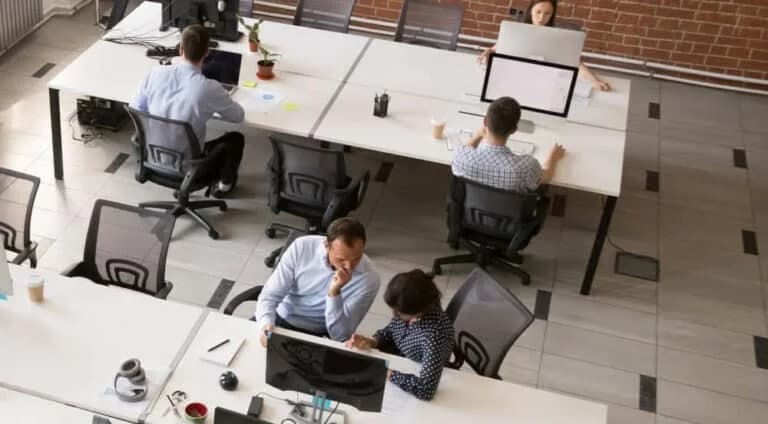 Employees working together in modern open office space, corporate group team employees using computers, talking, discuss project, colleagues in coworking, collaboration, teamwork concept, top view