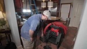 Technician preparing duct cleaning equipment in a residential kitchen to improve indoor air quality and prevent respiratory issues.
