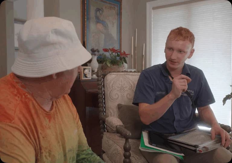 Technician discussing HVAC financing options with a customer in a cozy living room setting, featuring a clipboard and documents for reference.