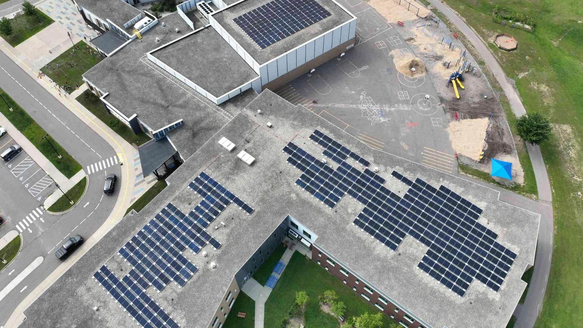 Aerial image showing completed rooftop solar arrays across the Bridges Elementary School buildings and playground areas.