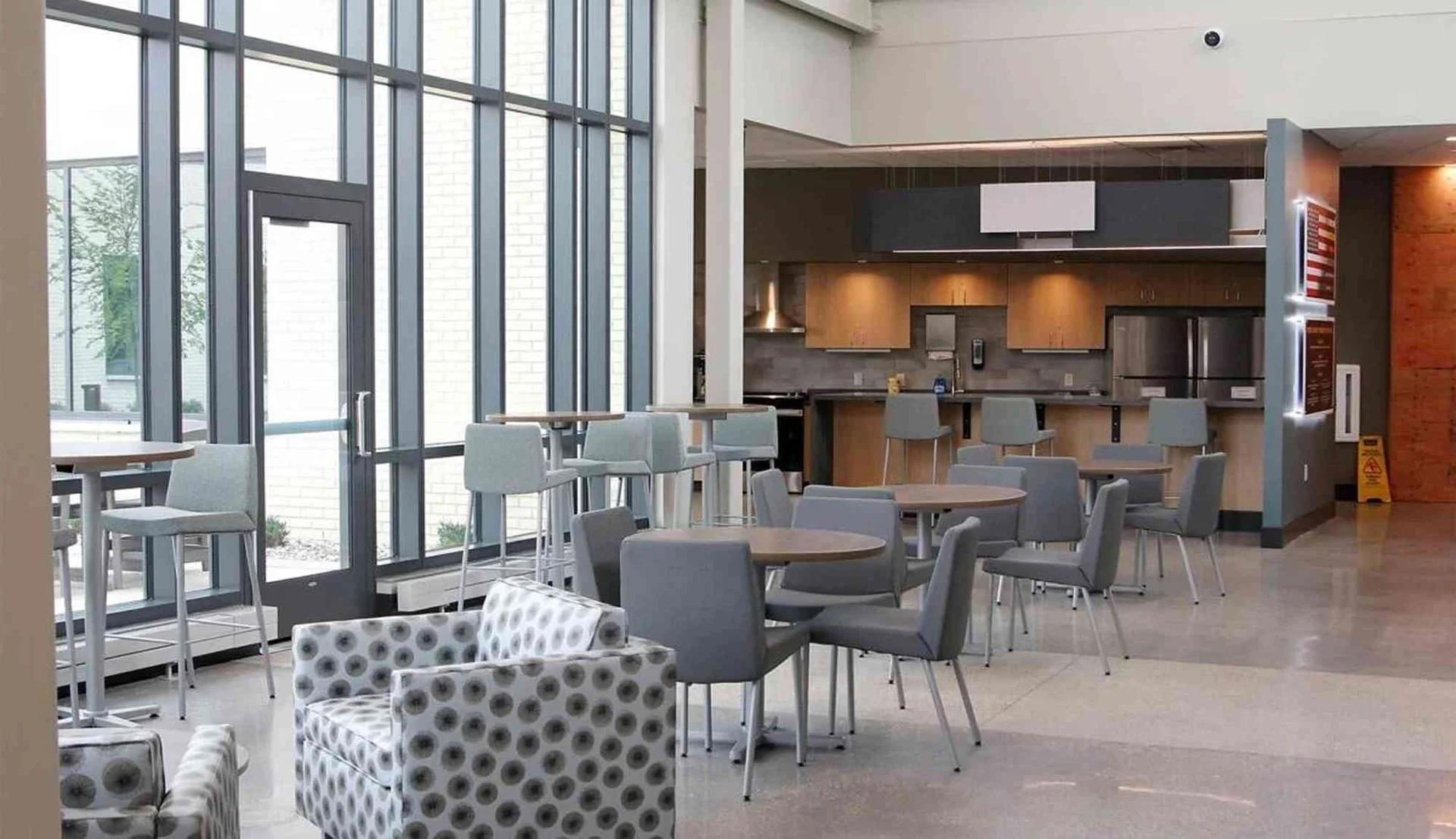 Interior lobby space with seating, tables, and natural light from large windows.