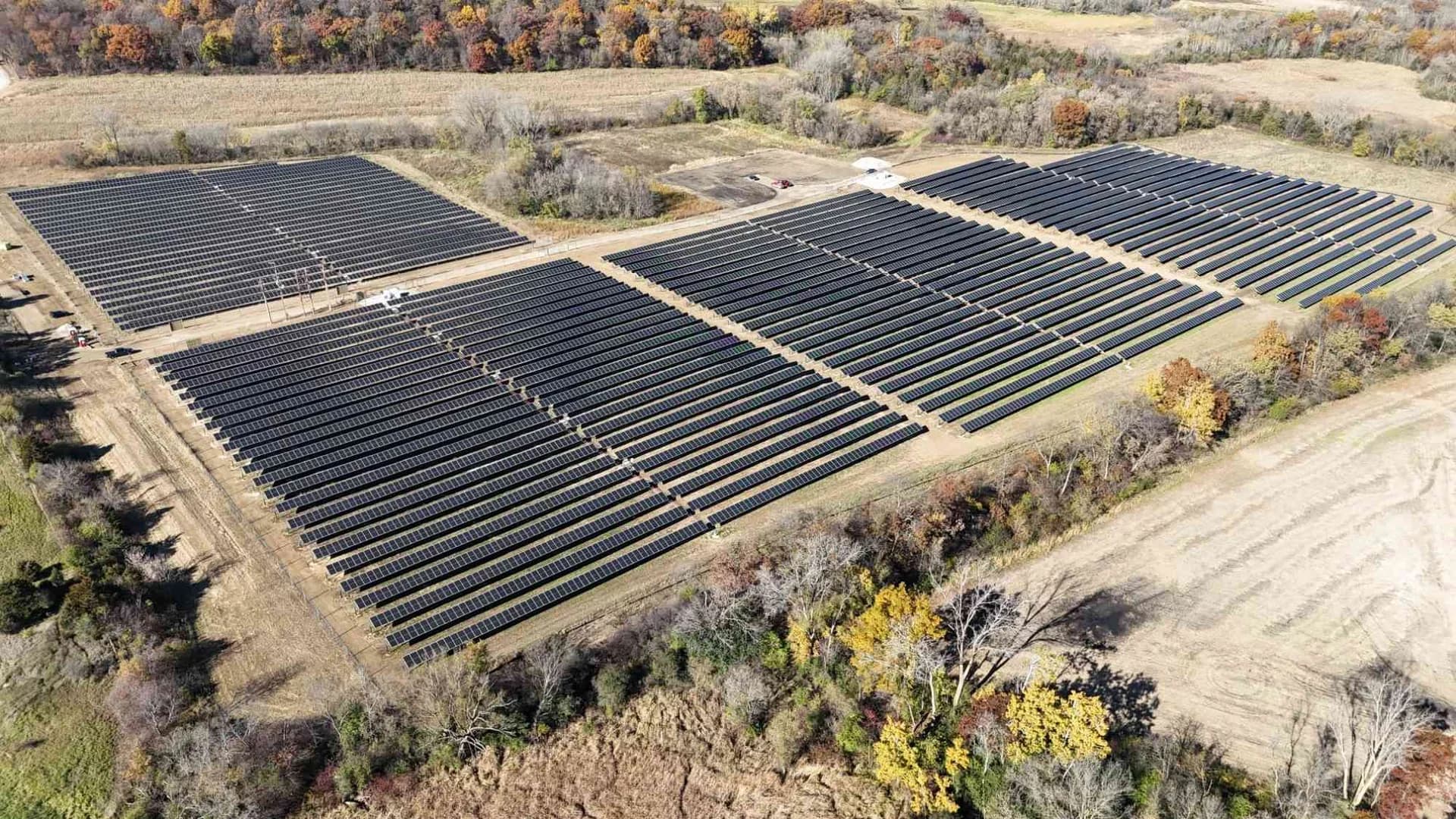 Aerial view of the Rock Lake Solar project in Waterloo, Wisconsin, showing rows of solar panels arranged in multiple large sections surrounded by fall foliage.