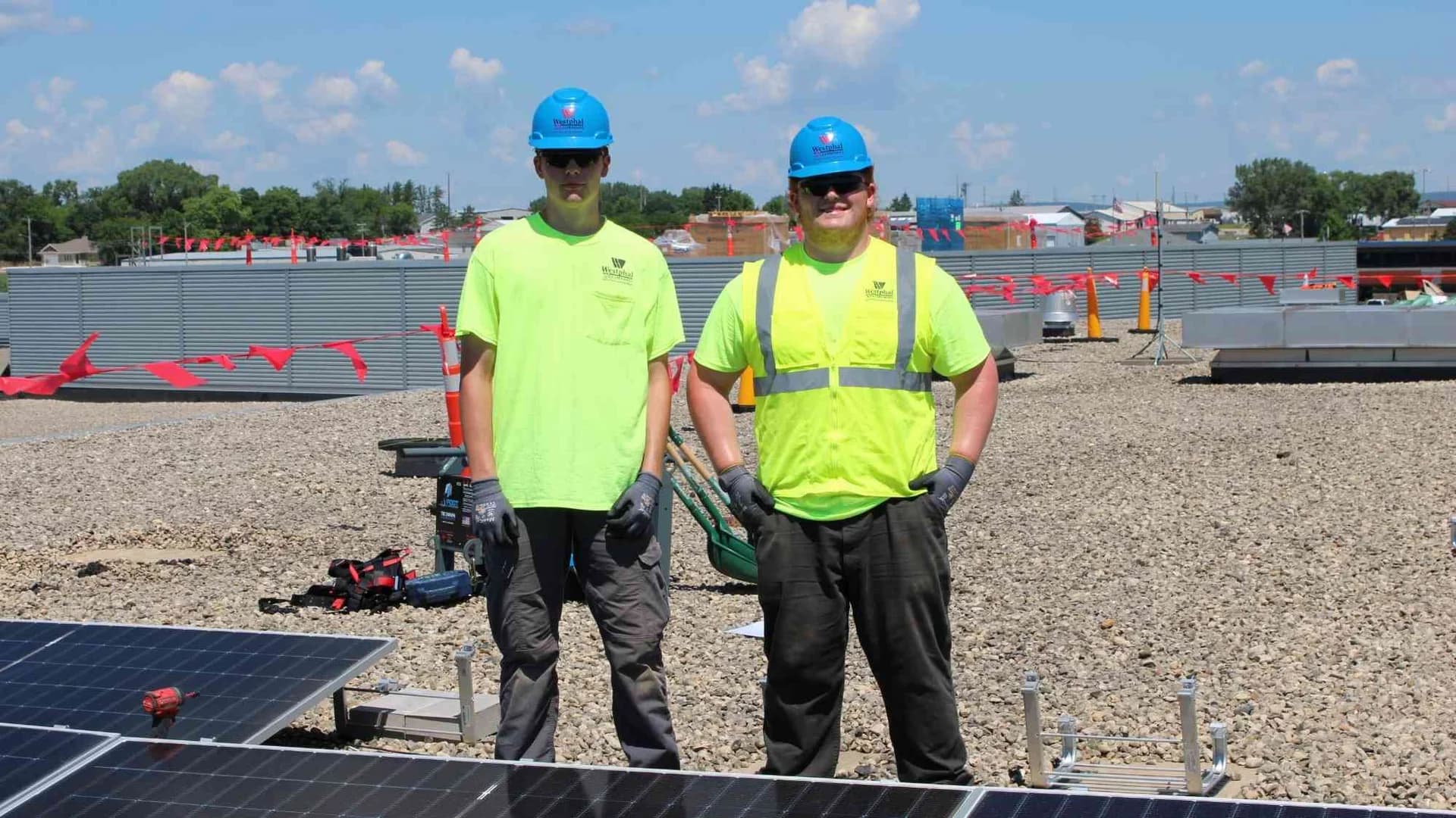 Two Westphal electricians standing beside rooftop solar equipment during installation at Bridges Elementary School.