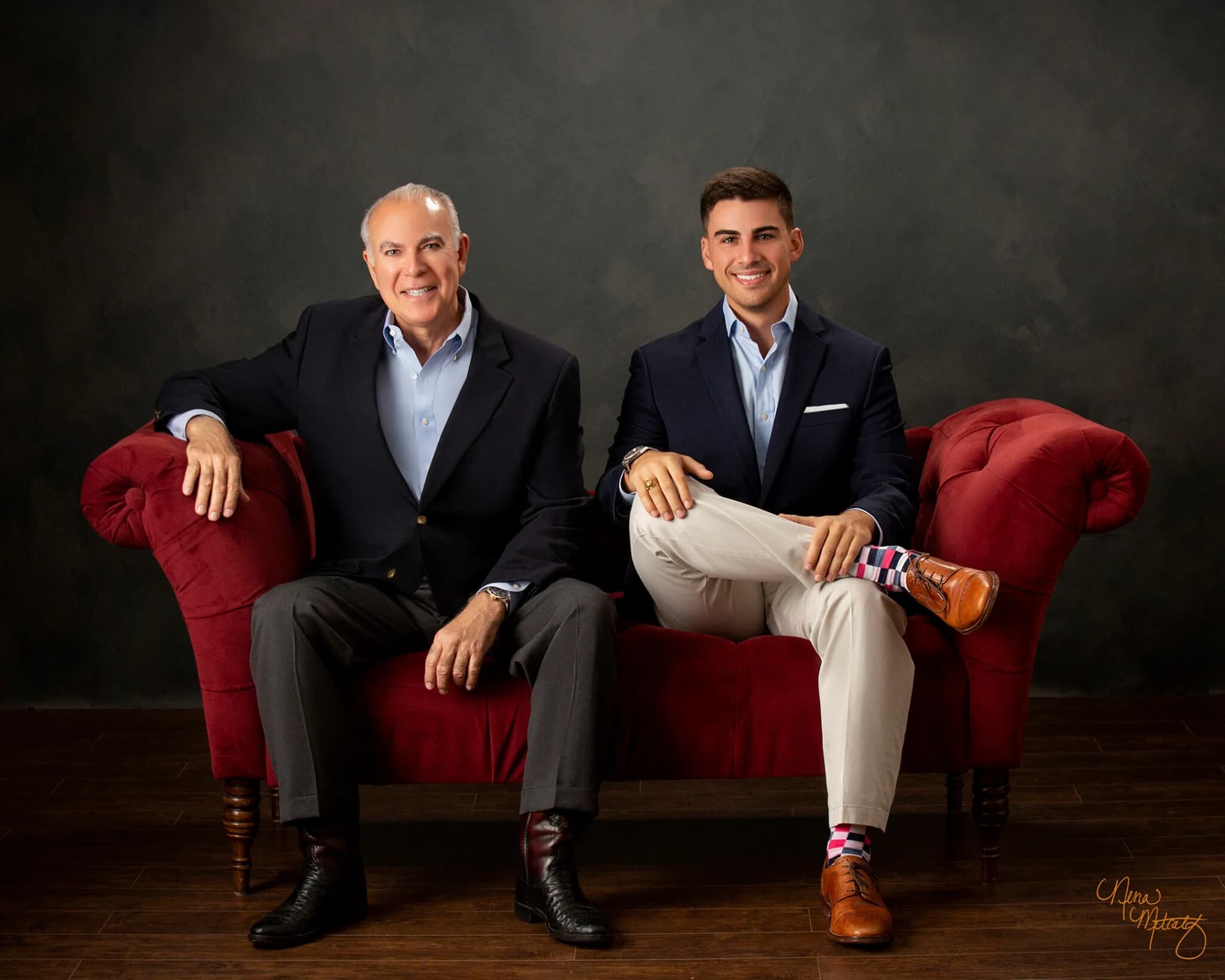sam and frank stilley, amstill owners, sitting on red couch smiling