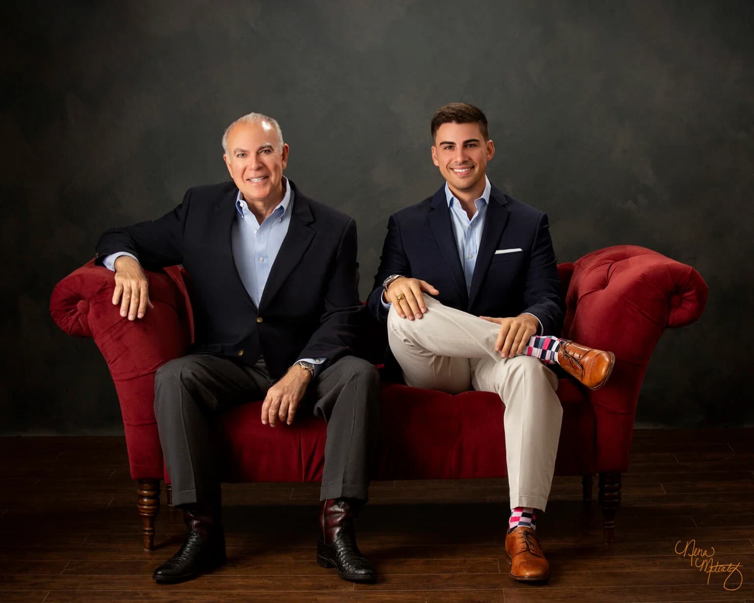 sam and frank stilley, amstill owners, sitting on red couch smiling