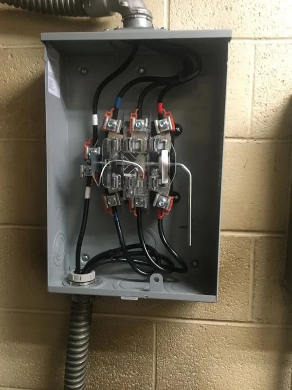 The electricity meter in a protective metal casing on a stone wall