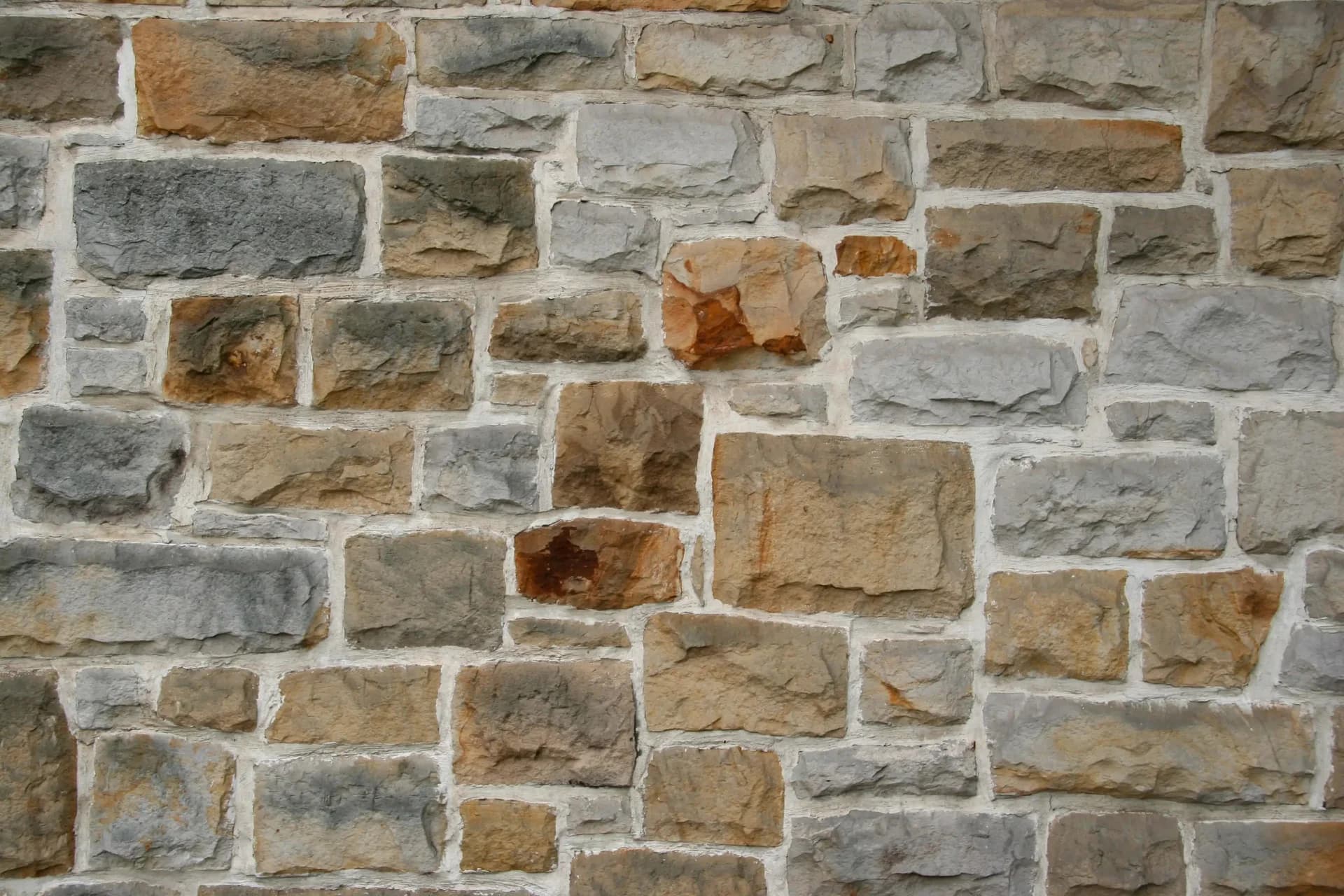 Close-up of a stone masonry wall featuring various sizes and colors of stones, showcasing traditional masonry craftsmanship