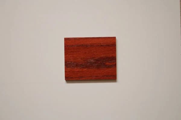 Red oak wood sample with a vibrant wild cherry stain, emphasizing the striking grain patterns and rich color depth, representative of C&S Cabinets' selection for luxurious custom cabinetry finishes.