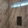 A beautifully tiled shower with large marble-pattern tiles and a built-in niche, installed by Orange Cat Flooring in Atlanta, GA.