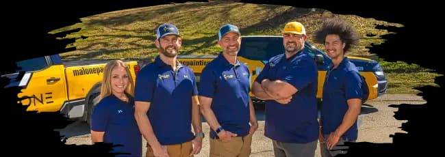 Malone Painting team standing in front of company trucks, smiling and wearing branded polo shirts