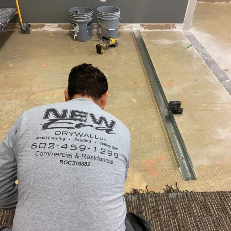 Phoenix Licensed and Bonded Drywall Installer wearing a New Era Drywall Company shirt prepares a floor for metal framing installation