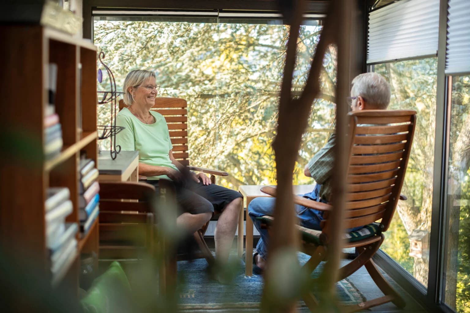 Senior couple sitting on wooden chairs in sun room