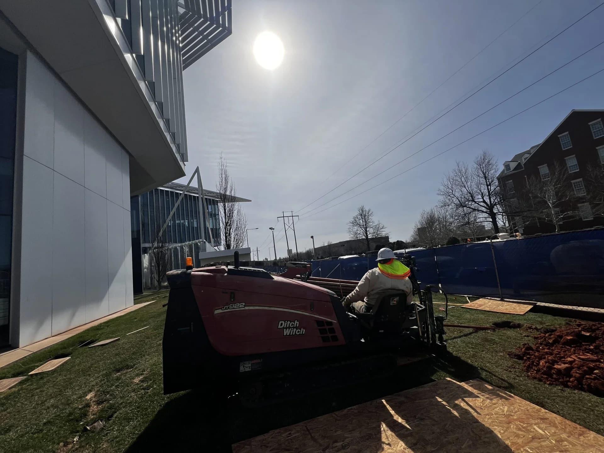 Trinity Boring Solutions Ditch Witch JT922 directional boring rig at modern commercial glass high-rise building Oklahoma