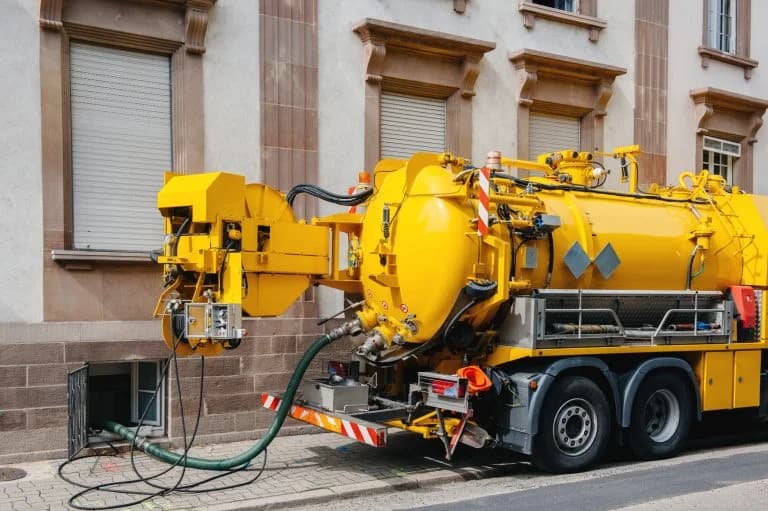 Sewerage truck on street working - clean up sewerage overflows, cleaning pipelines and potential pollution issues from an modern building.