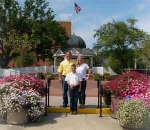 Family posing outdoors among vibrant flowers.