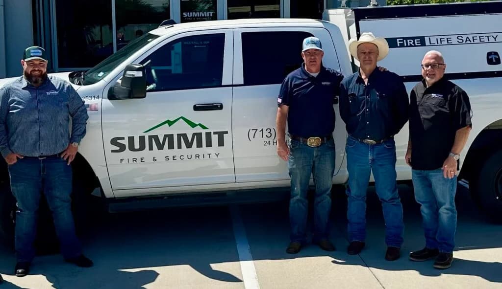Employees standing next to Summit Fire & Security truck