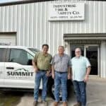 Three men in front of building.