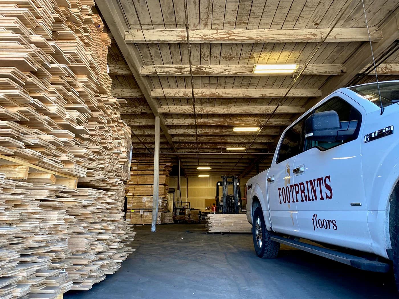 A Footprints pro standing next to one of our service vehicles - trust Footprints Floors, one of the best flooring installation companies to handle your next project.
